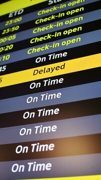 Airport departure board flashes delayed flight status among on time departures, alerting passengers to travel disruption.