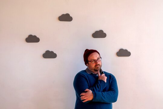 Contemplative man under cloud decor.