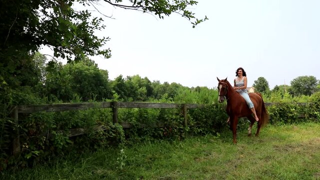 A woman rides bareback in a rural pasture on a summer day