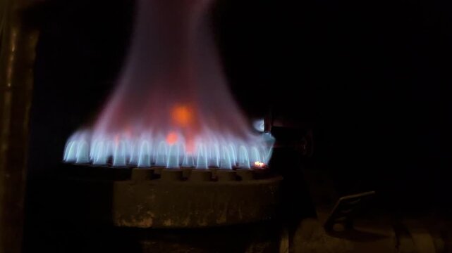 Close up of a vibrant blue gas flame burning steadily from a traditional domestic heater on a cold winter day