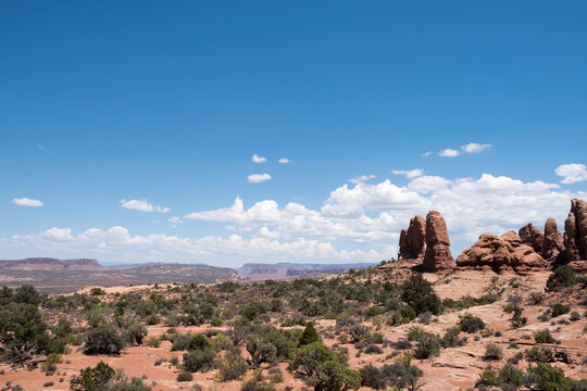 Large rock formations, blue sky, desert landscape with mountains in the far distance in Arches National Park in Moab, Utah.  Peaceful nature scene.