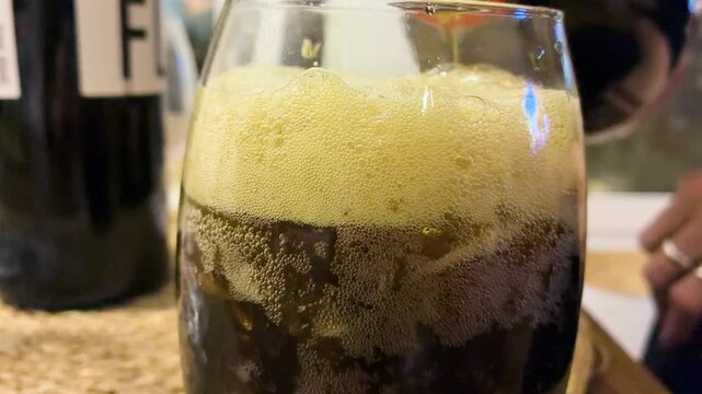 Close up of thick foam forming on top of traditional Fernet and cola alcoholic drink in a glass with ice, classic Argentine cocktail