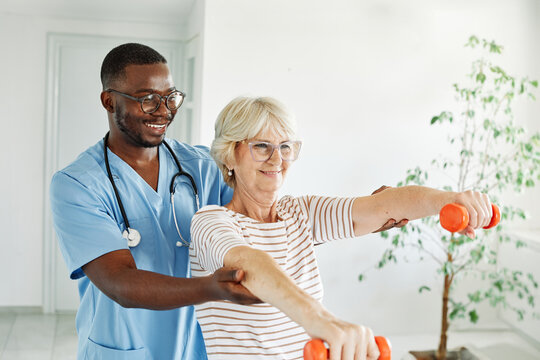 Doctor or nurse or physiotherapist caregiver exercise with senior woman at clinic or nursing home