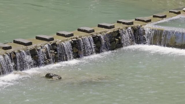 Flowing sulphur-rich water cascades over a stone barrier at Sahastradhara in Dehradun, a popular natural spring and wellness destination near ropeway and tapkeshwar temple