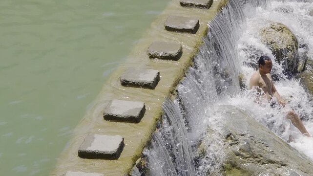 Dehradun, India - 13th May'26: Flowing sulphur-rich water cascades over a stone barrier at Sahastradhara in Dehradun, a popular natural spring and wellness destination near ropeway and tapkeshwar temp