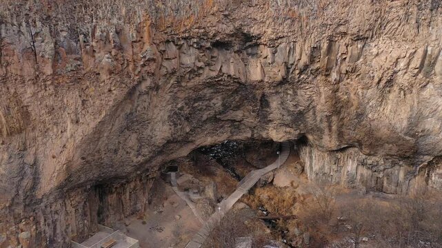 Aerial drone footage capturing the magnificent Devil's Bridge and Vorotan River Canyon in Armenia, showcasing the unique natural rock formations, towering steep cliffs,and winding scenic mountain road