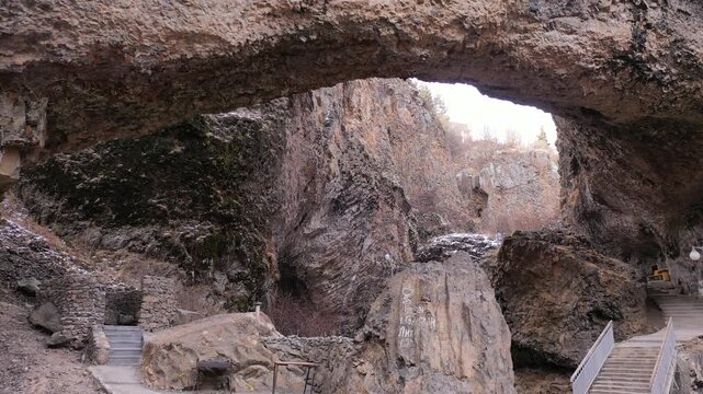 Aerial drone footage capturing the magnificent Devil's Bridge and Vorotan River Canyon in Armenia, showcasing the unique natural rock formations, towering steep cliffs,and winding scenic mountain road