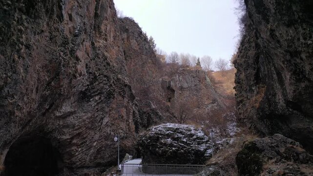 Aerial drone footage capturing the magnificent Devil's Bridge and Vorotan River Canyon in Armenia, showcasing the unique natural rock formations, towering steep cliffs,and winding scenic mountain road