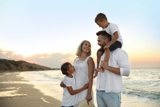 Happy family on sandy beach near sea at sunset