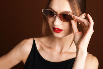 Fototapeta premium Beautiful woman in stylish sunglasses on brown background
