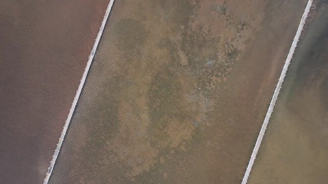 Top down aerial view of Pag saltworks highlighting colorful salt basins and the geometric layout of the production fields