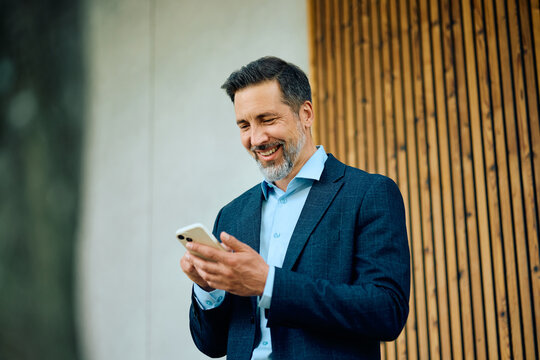 Happy businessman using smart phone.