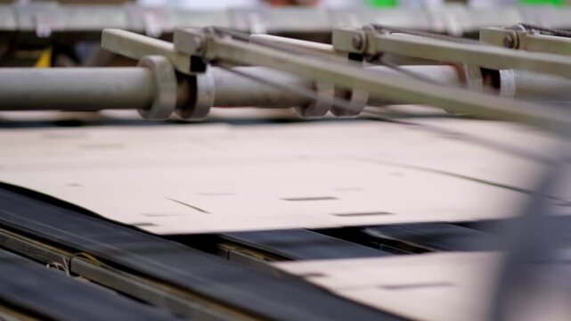Die cut corrugated cardboard sheets moving along a fast automated conveyor system for box assembly in a manufacturing plant.