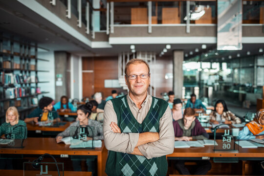 Professor standing in university library with students studying