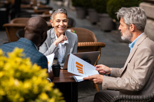 Mature business colleagues discussing reports at outdoor cafe
