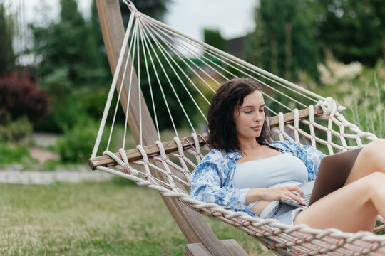 Beautiful woman resting comfortably in a hammock after remote work with a laptop nearby. Digital nomad lifestyle, work-life balance