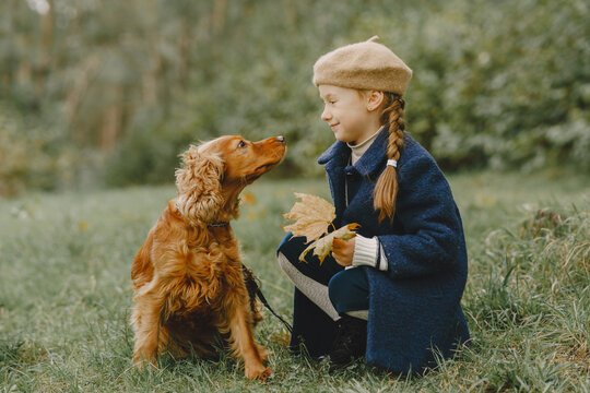 Little girl walks in autumn forest with a dog