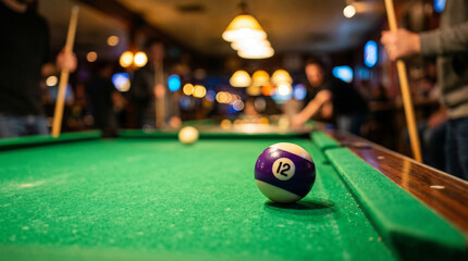 Close-up of number 12 pool ball on green table in a bar © Arqam