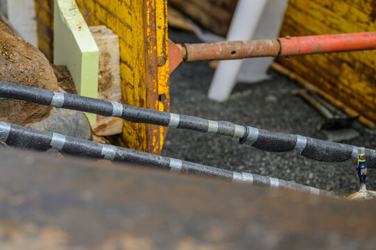 Insulated utility cables crossing active city construction trench.