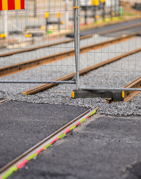 Construction fence and tram tracks at urban rail worksite.