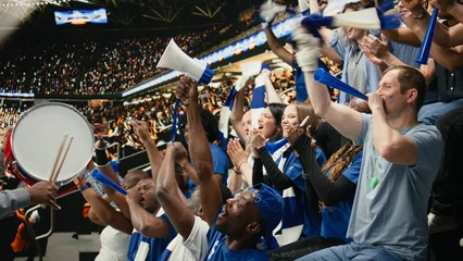 Fototapeten Restaurant Passionate football capo beating drum and directing blue supporter, group from stadium stands during coordinated chant at live soccer match.  © DC Studio