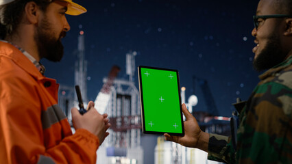 Green screen tablet used by military man on drilling rig with walkie talkie enforcing maritime blockade, soldier using mockup device and handheld radio on offshore rig during oil crisis, camera A. © DC Studio