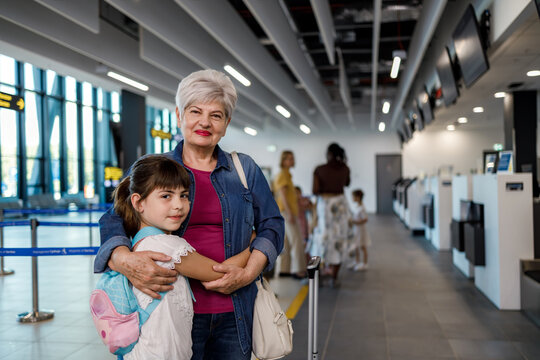 Grandmother and granddaughter wait at airport check-in area for their flight to vacation destination