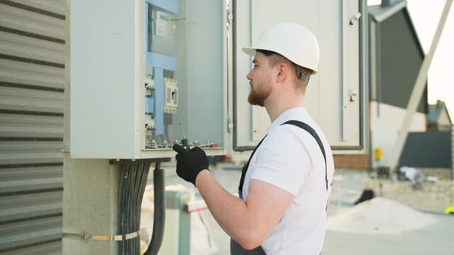 Electrician assembling breakers in electrical panel at construction site