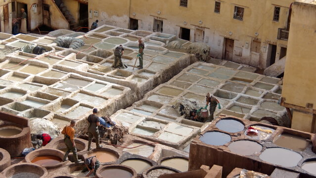 Workers at the square chemical vats for softening leather at the Chouara Tannery in the medina, in Fes, Morocco