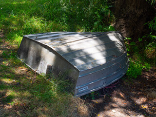 Upside down aluminum dinghy boat on green grass © mcgimpseymike