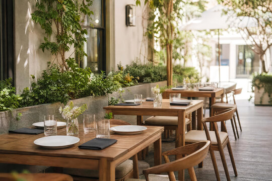 Faded Outdoor Restaurant Patio With Wooden Tables And No Food With Greenery Photographed In Bright Commercial With Layered Restaurant Depth