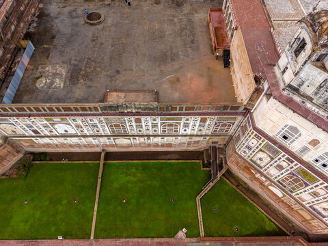 Aerial view of the historic Lahore Fort featuring intricate wall tile work, a large courtyard, and a manicured green lawn in Lahore, Punjab, Pakistan.