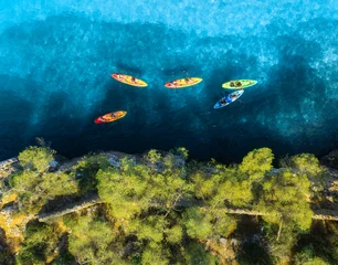Aerial drone view of colorful kayaks in crystal clear turquoise sea near rocky coast and green trees. Summer outdoor adventure in Mallorca, Balearic Islands, Spain. Top down view of canoes. Vacation © den-belitsky