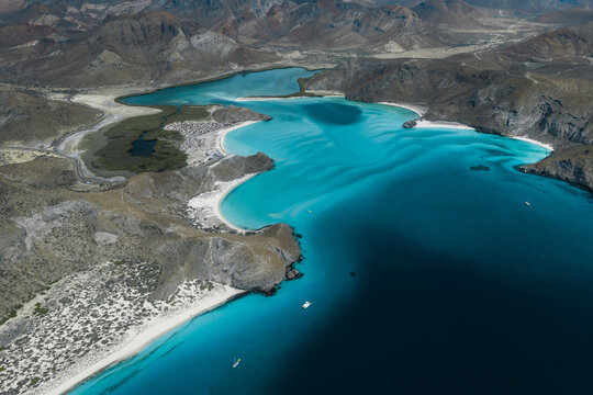 Aerial view of the turquoise waters and white sand beaches of Balandra Beach surrounded by arid hills in La Paz, Baja California Sur, Mexico.