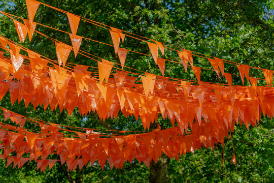 Football fever concept, Supporter hanging pennant orange flags, (Originally symbolize the Dutch) as decoration above overhead between the buildings in city, Netherlands national football team, Holland