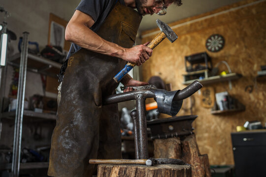 Craftsman hammering metal creating traditional hand forged product