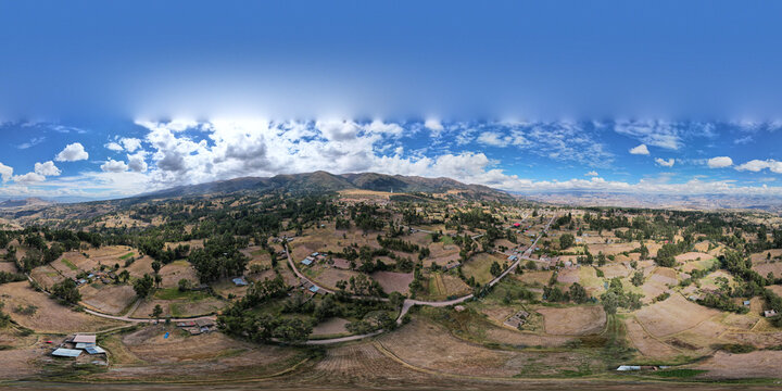 Aerial view of the rural landscape surrounding Ayacucho with agricultural fields, scattered trees, and rolling hills under a blue sky in Ayacucho, Ayacucho, Peru.
