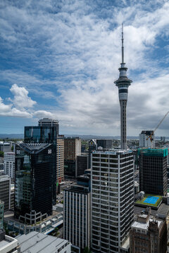 A construction crane rises alongside Auckland's Sky Tower as the city pursues ambitious urban development targets, amid a housing affordability crisis driving record emigration of young New Zealanders