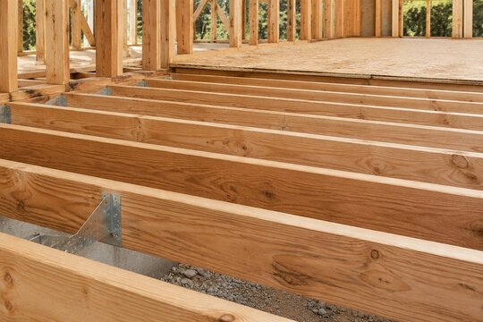 Exposed wooden joists supporting an unfinished floor on a construction site.