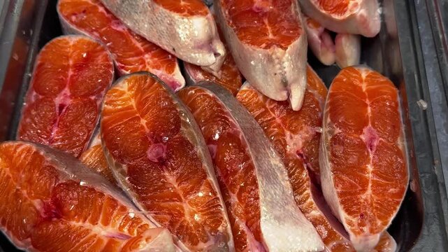 Fresh salmon steaks on a black tray, chilled at the market on the supermarket counter. Close-up