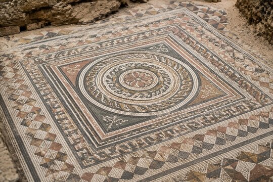 Close-up of ancient mosaic floor with geometric patterns, archaeological texture.