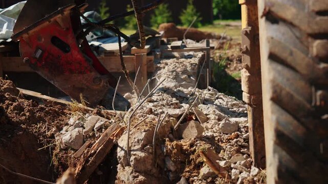 Heavy duty hydraulic hammer breaking old reinforced concrete foundation into pieces. Industrial machinery at work during a building demolition process, with dust and debris flying around