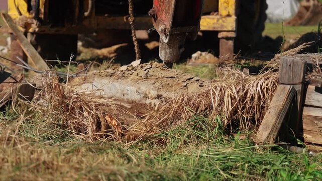 Powerful hydraulic breaker attached to an excavator smashing an old concrete foundation on a construction site. Heavy machinery is crushing stone and rock during demolition and renovation work