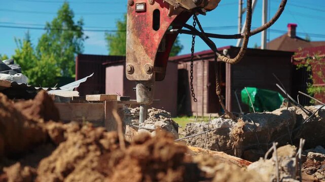 Close-up of a hydraulic breaker driving through a reinforced concrete foundation with exposed twisted rebar during residential demolition, showing structural removal, heavy equipment and site cleanup.