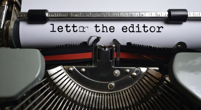A close-up view of a vintage typewriter with a sheet of white paper displaying the text letter the editor being typed