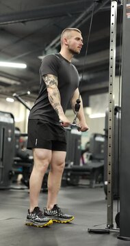 Strong man training on lat pulldown machine in gym, low angle view