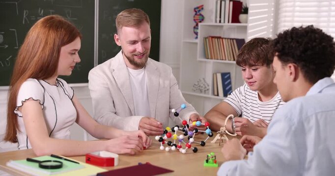 Teacher showing molecular model to students during physics lesson in classroom