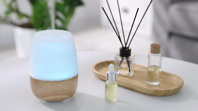 Aromatherapy. Modern aroma lamp, reed diffuser and bottles of essential oils on light table indoors, closeup