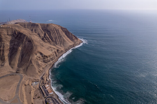 Aerial view of the Malecon de Chorrillos coastal cliffs meeting the Pacific Ocean, with winding roads and urban infrastructure in Lima, Provincia de Lima, Peru.