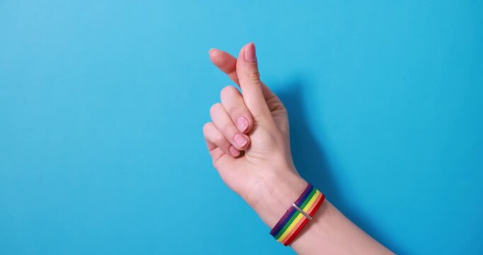 LGBT concept. Woman showing heart gesture on light blue background, closeup
